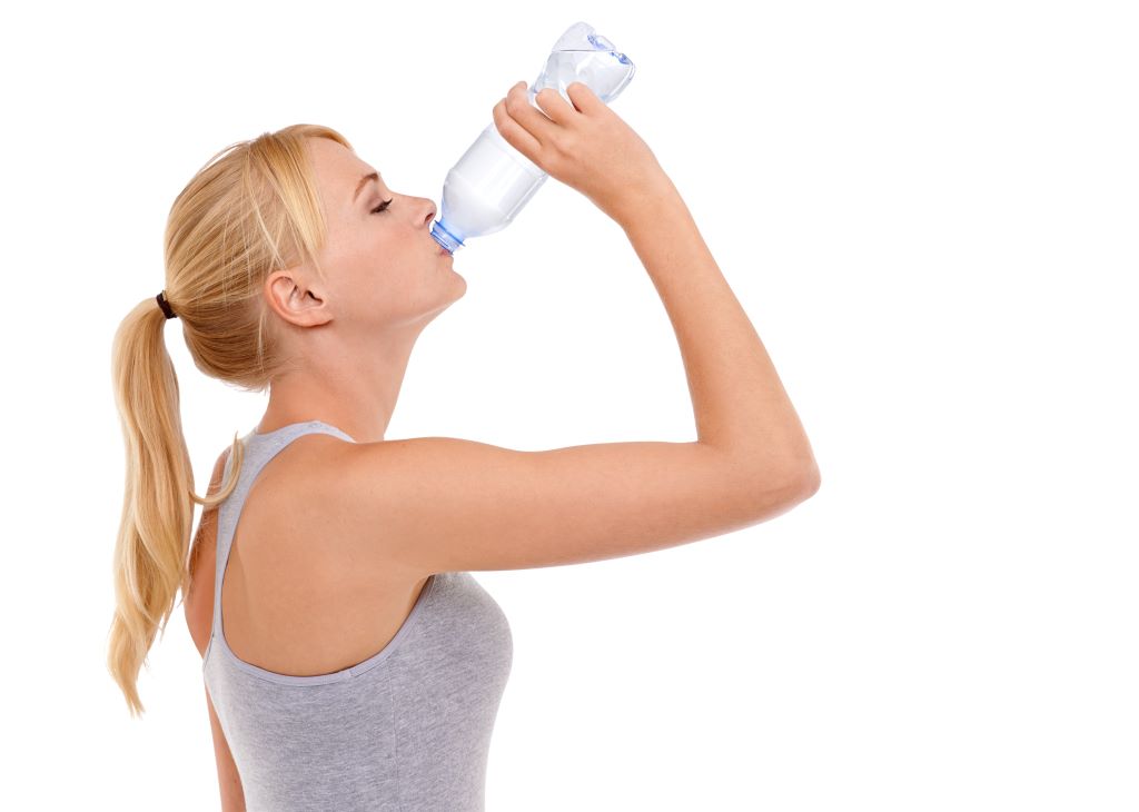 Blonde Frau in Sportkleidung trinkt aus einer Wasserflasche