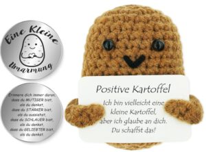 Gestrickte Kartoffel mit einem Schild in den Händen, auf dem eine positive Botschaft steht.